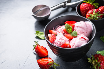 Strawberry ice cream with fresh berries on black.