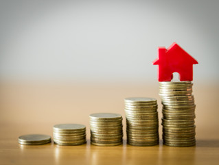 Home model on the growing coin stack for concept of money saving for home buying fund