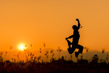 Happy woman jumping and sunset silhouette with copy space.