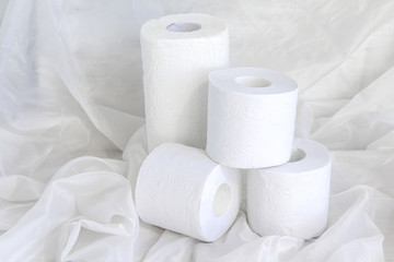 White paper towel rolls, toilet paper stack on draped cloth.