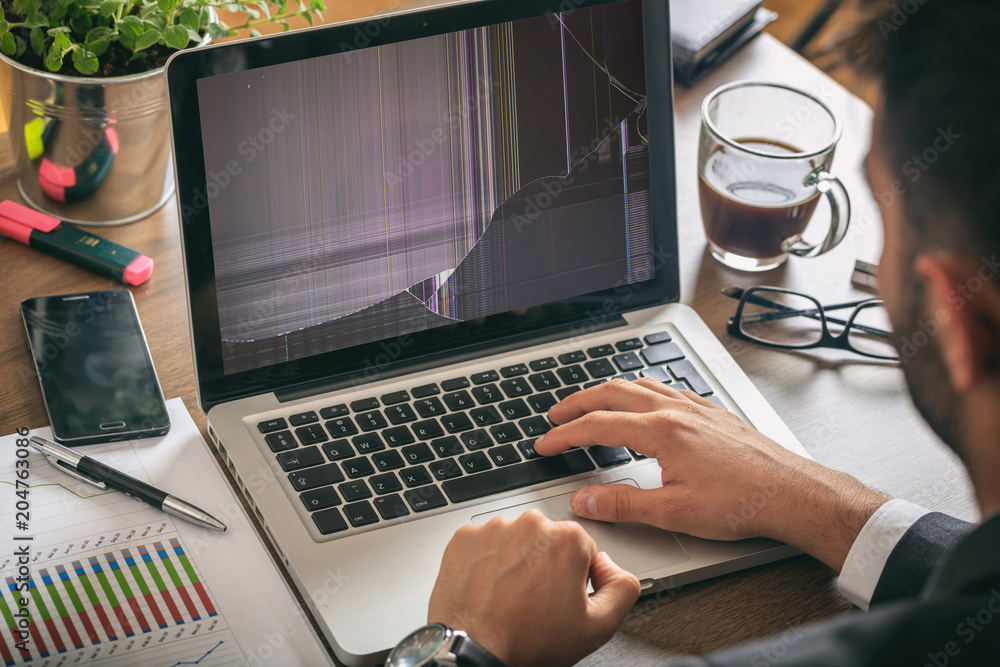 Poster man working with a broken laptop computer on office business background
