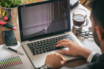 Man working with a broken laptop computer on office business background