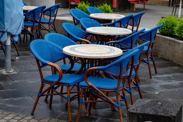 Tables with several blue chairs on the terrace of an ice cream parlor