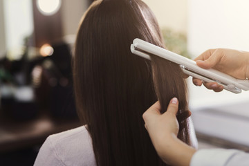 Hair straightening by a hairdresser in a professional salon,