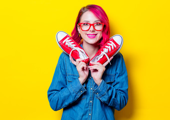 Young pink hair girl in blue shirt and red glasses holding a wishes gumshoes. Portrait isolated on...