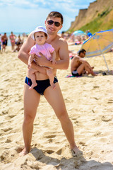 Young father in sunglasses on the beach with a little daughter