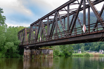 Rusty metal train bridge over a small river 