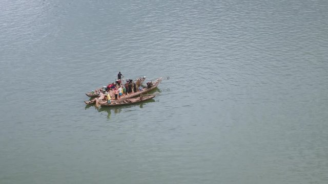 Upper view on fishers in small boats lifting together a large net out of water