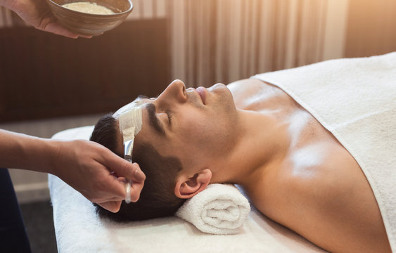 Man getting face mask by beautician at spa