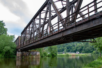 Rusty metal train bridge over a small river 