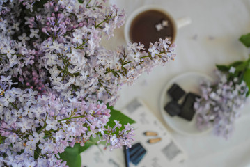 Notepad, a cup and a bouquet of lilac on the table