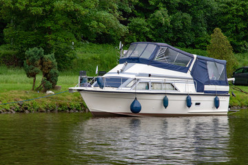 Single litte white boat swimming on a small river 