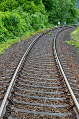 Fototapeta premium Railway with a stony railbed in the green forest