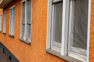 Fototapeta na wymiar Orange house facade with windows and shutters 