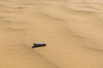 Old rusty bullet cartridge case in sand close. Concept: armed conflicts in the Middle East