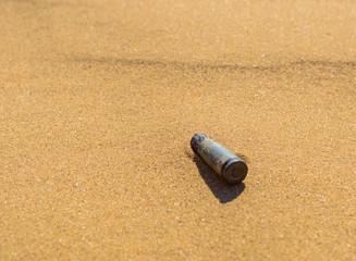 Old rusty bullet cartridge case in sand close. Concept: armed conflicts in the Middle East