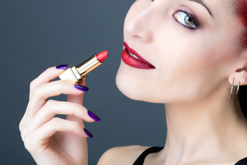 Obraz premium Portrait d'une jeune femme appliquant du rouge à levre