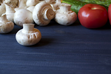 Vegetables on a table. Mushrooms, tomatoes and cucumbers on a blue rustic background.