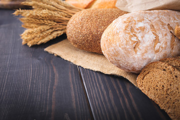 Fresh bread and wheat on the wooden table.
