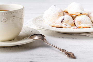 Baked sweet patty filled with berry jam on a plate. Small berry pie, variety of bakery on the background