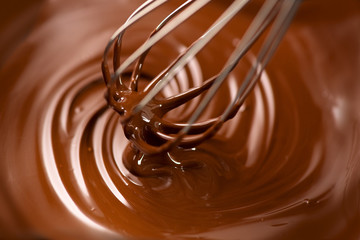 Chocolate. Mixing melted dark chocolate with a whisk. Closeup of liquid hot chocolate swirl....