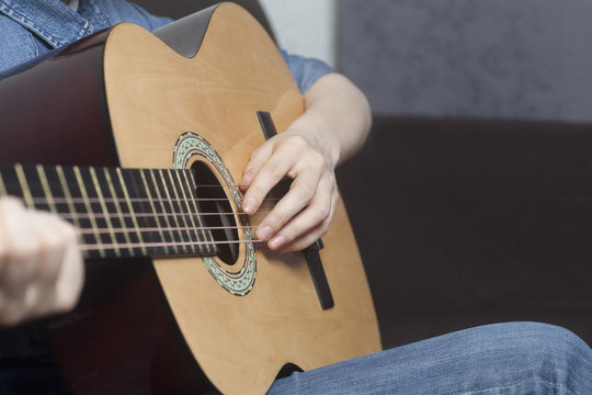 Young womans hands playing a acoustic classic guitar
