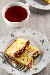 sliced cake with almonds and blueberries on a white ceramic plate with a Cup of tea
