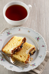 sliced cake with almonds and blueberries on a white ceramic plate with a Cup of tea