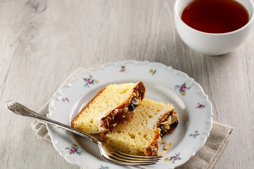 sliced cake with almonds and blueberries on a white ceramic plate with a Cup of tea