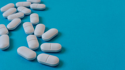 Obraz na płótnie Canvas White Oval pills on blue background. Medicine and healthy