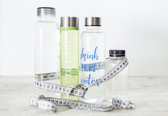 Bottles of water with tape measure on the white background