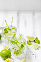 Summer refreshing cocktail mojito with lime and mint on white wooden vintage background.