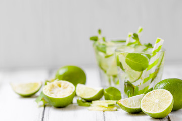 Summer refreshing cocktail mojito with lime and mint on white wooden vintage background.