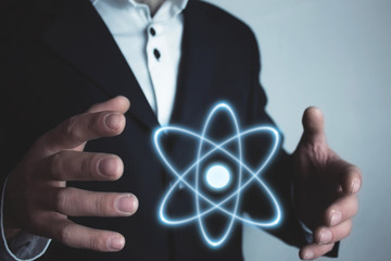 Caucasian businessman holding atom. Power and innovation concept