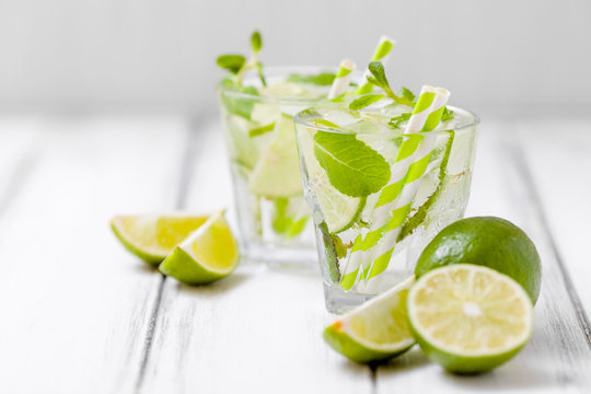 Summer refreshing cocktail mojito with lime and mint on white wooden vintage background.