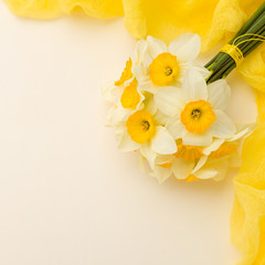 White daffodil bouquet with yellow textile decoration on pastel background with copy space.