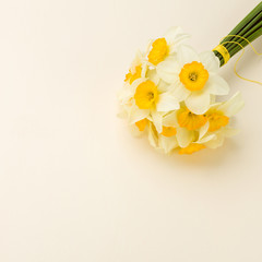 White daffodil bouquet on yellow pastel background with copy space.