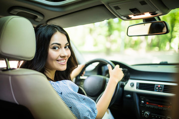 Fototapeta na wymiar Portrait of beautiful smiling woman driving a car on street