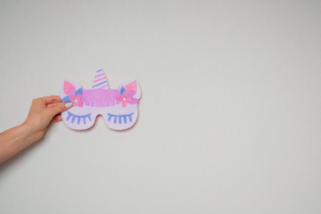 A hand holds a mask for sleeping with a unicorn. Copy space