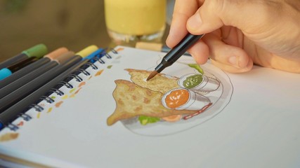 Male designer drawing food sketches, close-up.