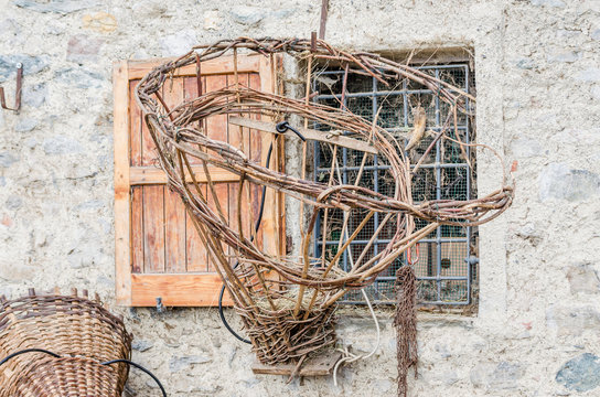 An old gerla hanging in front of a window of a mountain shelter. It is an old wooden basket used in the past to transport hay by farmers in the Alps
