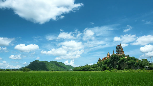 Landscape of lush green rice field and surrounding mountains at Wat Thum Sua temple (tiger cave temple) in Kanchanaburi, Thailand