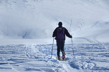 Fototapeta na wymiar One man walking with ski over the snow land to the mountain view from back