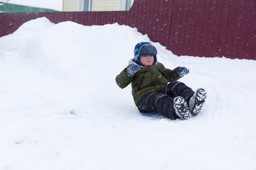 Fototapeta na wymiar Boy goes for a drive on a snowy hill