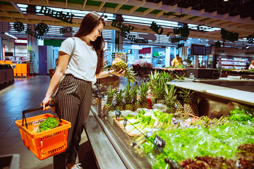 woman choosing pineapple in grocery store