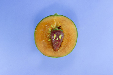 A strawberry inside a juicy melon, with  an happy face made with seeds.