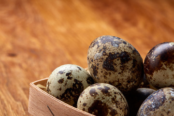 Quail eggs in a box on a rustic wooden background, top view, selective focus.