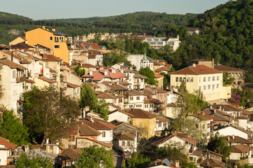 View at old town of Veliko Tarnovo, Bulgaria. Old houses with tile roofs highlighted with sun. Lovely spring evening.