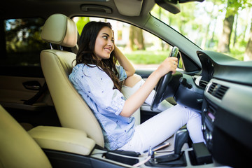 Naklejka premium Young woman ooking over her shoulder while driving a car