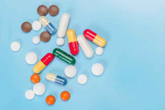 Medicines of different colors and forms, on a light blue background